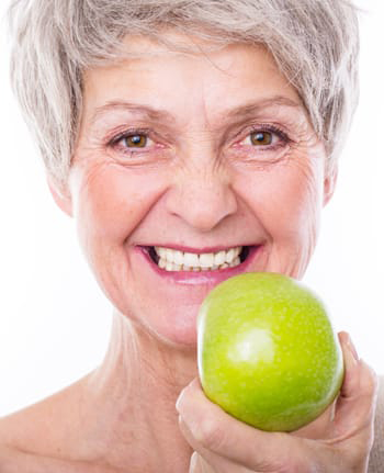 woman with an apple displaying full mouth reconstruction