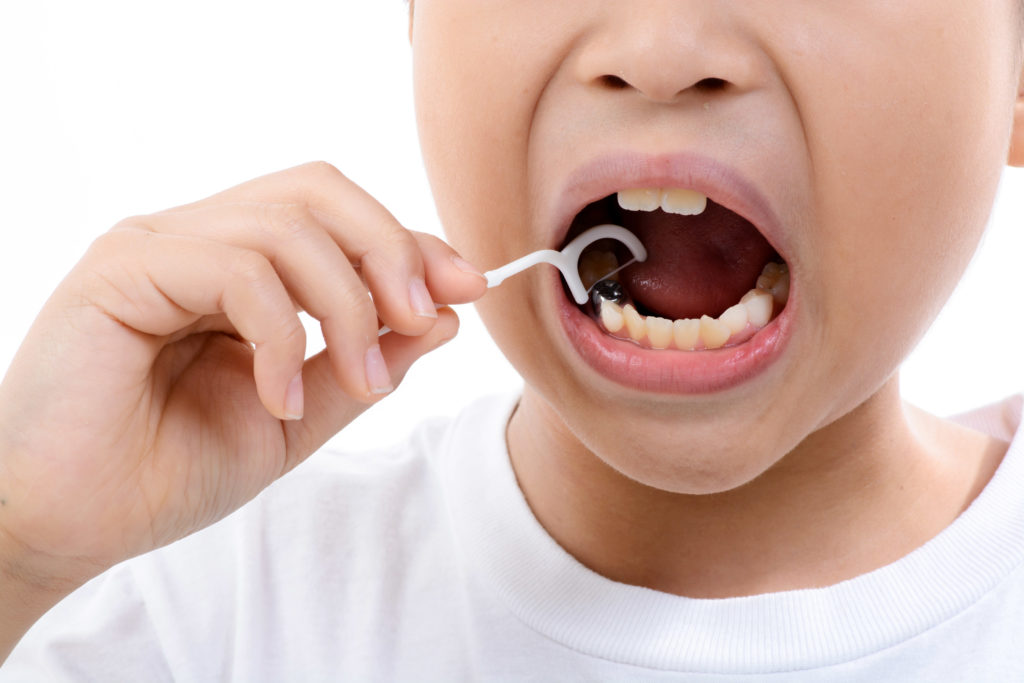 Close up Young asian boy useing toothpick to clean his teeth on white background.