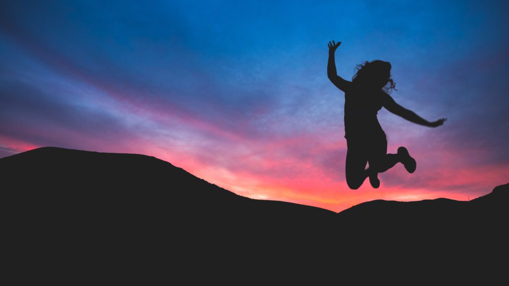 Stock Photo of a Silhouetted Woman jumping in front of a sunset.